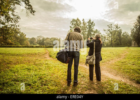 Caucasian couple standing on trail in park with camera Stock Photo