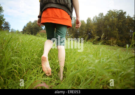 Close up of barefoot Caucasian woman walking in park Stock Photo