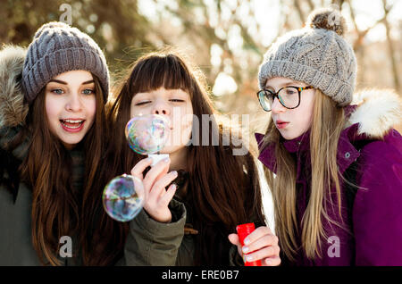 Caucasian girls blowing bubbles outdoors in winter Stock Photo