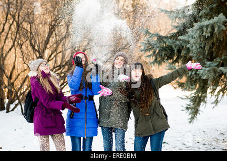 Caucasian girls throwing snow in field Stock Photo