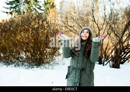 Caucasian girl throwing snow in field Stock Photo