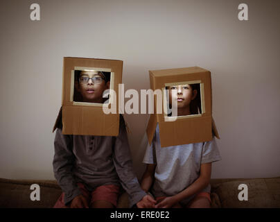Mixed race brother and sister wearing cardboard box astronaut helmets Stock Photo