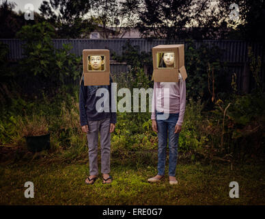 Mixed race children wearing cardboard astronaut helmets in backyard Stock Photo