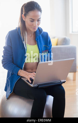 Caucasian woman using laptop in gym Stock Photo