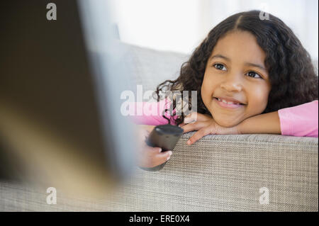 Mixed race girl watching television on sofa Stock Photo