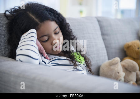 Sad mixed race girl sitting on sofa Stock Photo