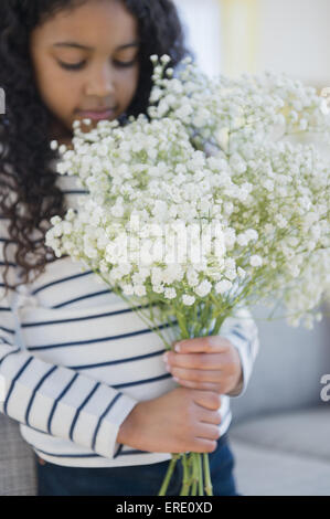 Mixed race girl holding bouquet of flowers Stock Photo