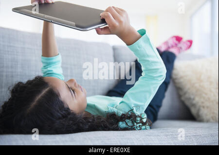 Mixed race girl using digital tablet on sofa Stock Photo
