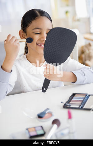 Mixed race girl applying makeup with brush Stock Photo