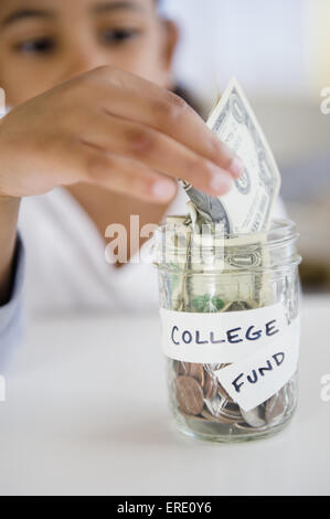 Mixed race girl saving money in college fund jar