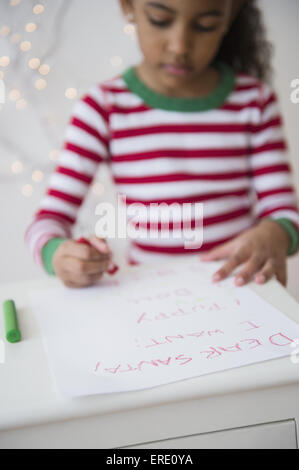 Mixed race girl writing letter to Santa Stock Photo