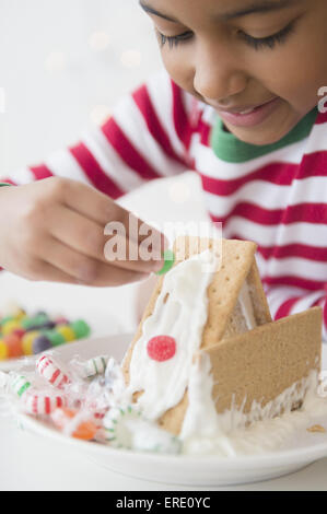 Mixed race girl decorating gingerbread house Stock Photo