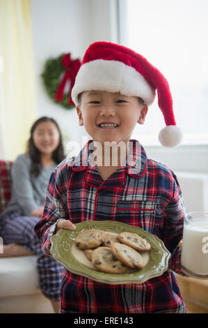 Asian boy holding plate of cookies for Santa Stock Photo