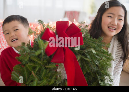 Asian brother and sister carrying Christmas wreath Stock Photo