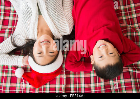 Asian brother and sister laying on blanket at Christmas Stock Photo