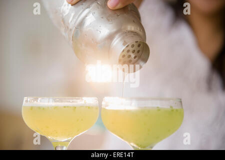 Pacific Islander woman pouring cocktails from shaker Stock Photo