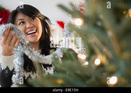 Pacific Islander woman decorating Christmas tree Stock Photo
