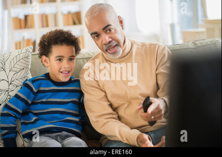 Mixed race grandfather and grandson watching television Stock Photo