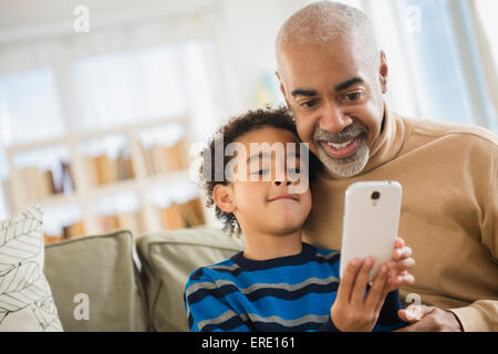 Mixed race grandfather and grandson using cell phone Stock Photo