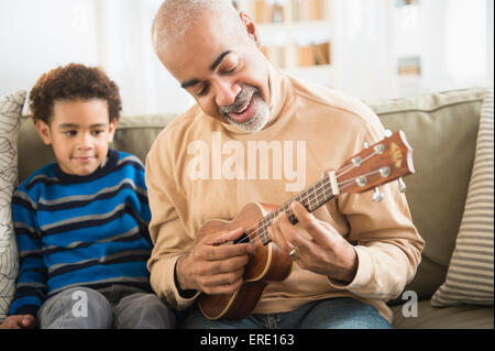 Mixed race grandfather and grandson playing ukulele Stock Photo