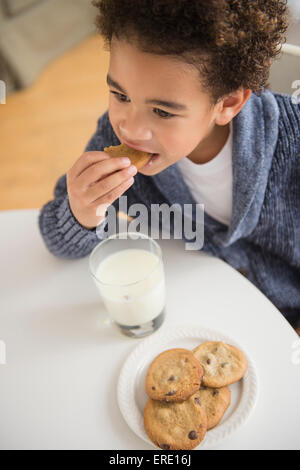 Mixed race boy eating cookies and milk Stock Photo