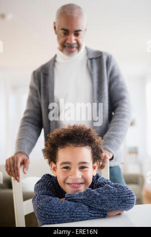 Mixed race grandfather and grandson sitting at table Stock Photo
