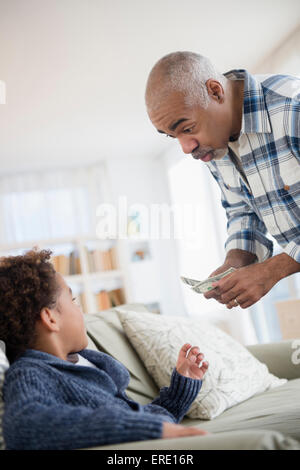 Mixed race grandfather giving money to grandson Stock Photo