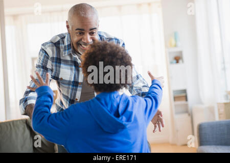 Mixed race grandfather and grandson greeting in living room Stock Photo