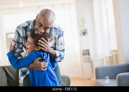 Mixed race grandfather and grandson hugging in living room Stock Photo