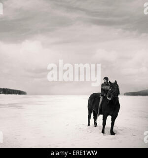 Caucasian girl riding horse in snowy field Stock Photo