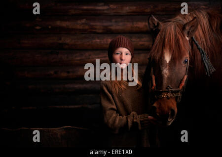 Caucasian girl standing with horse in barn Stock Photo
