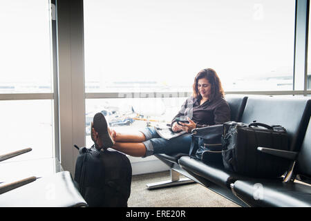 Hispanic woman texting on cell phone in airport Stock Photo