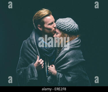Smiling couple wrapped in blanket kissing