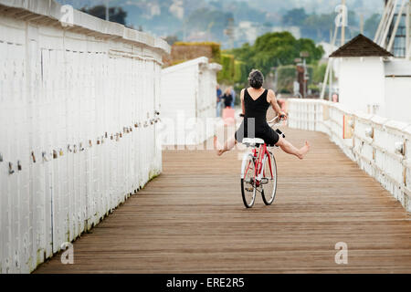 Older Caucasian woman riding bicycle on wooden dock Stock Photo