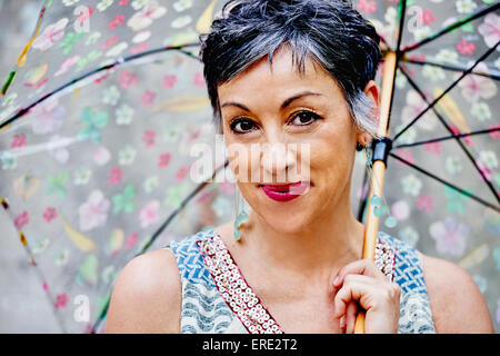 Older Caucasian woman posing with umbrella Stock Photo