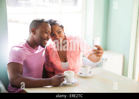 Smiling couple taking cell phone selfie at table with coffee Stock Photo
