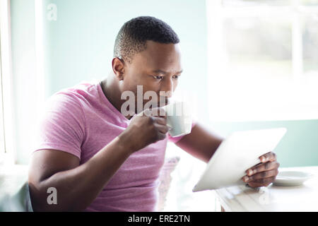 Black man drinking coffee using digital tablet Stock Photo