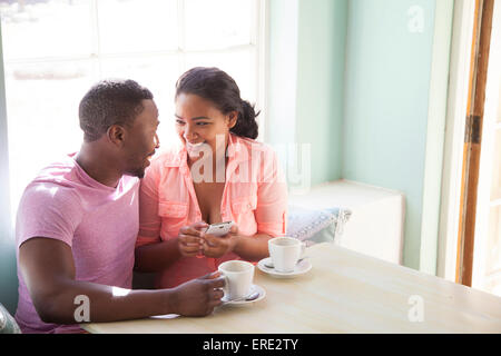 Smiling couple using cell phone at breakfast Stock Photo