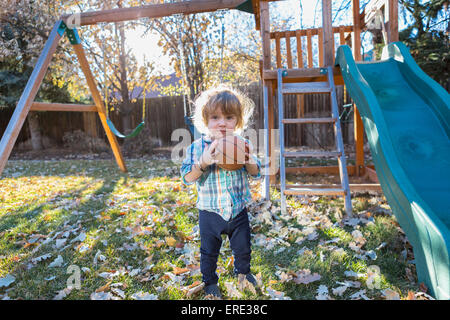 Caucasian boy holding basketball in backyard Stock Photo