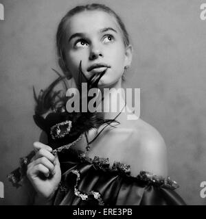 Caucasian girl holding feather mask Stock Photo
