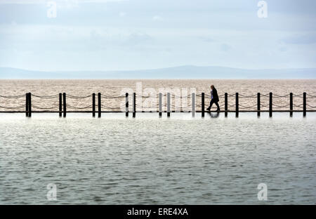 Walk the Line. A person walks across the causeway separating the Marine Lake from the sea in Weston-super-Mare. Stock Photo
