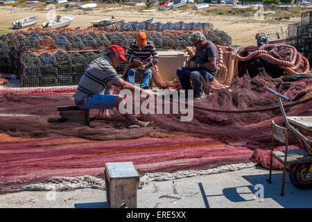 3 fishermen repairing their nets for the next days fishing Stock Photo