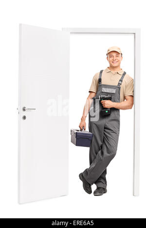 Full length portrait of a young male worker holding a toolbox and a hand drill and leaning against the frame of an open door Stock Photo