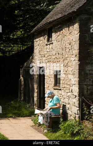 UK, England, Staffordshire, Dovedale, Milldale visitor sat reading in sun outside National Trust information barn Stock Photo