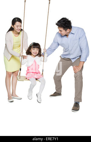 Young parents pushing daughter on swing Stock Photo
