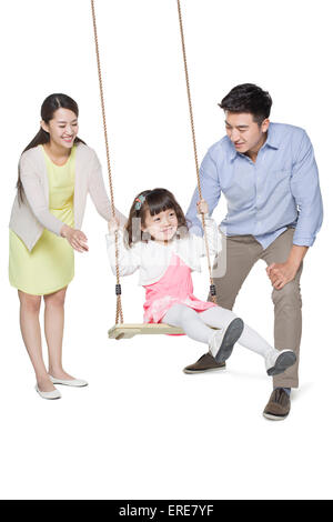 Young parents pushing daughter on swing Stock Photo