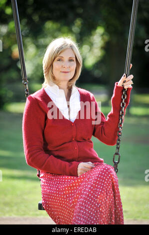 A woman in red sat on a swing in a park. Stock Photo