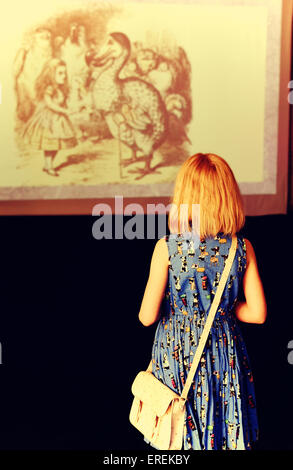 The silhouette of little girl  on the background of picture from the 'Alice in Wonderland' book. Stock Photo