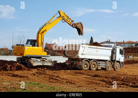 industrial excavator loading tipper truck on construction site Stock Photo