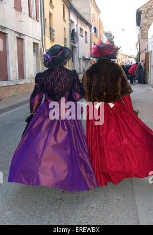 Two ladies in Victorian costumes (back view) taking part in a Valentine's Day parade in the village of Roquemaure, Southern Stock Photo